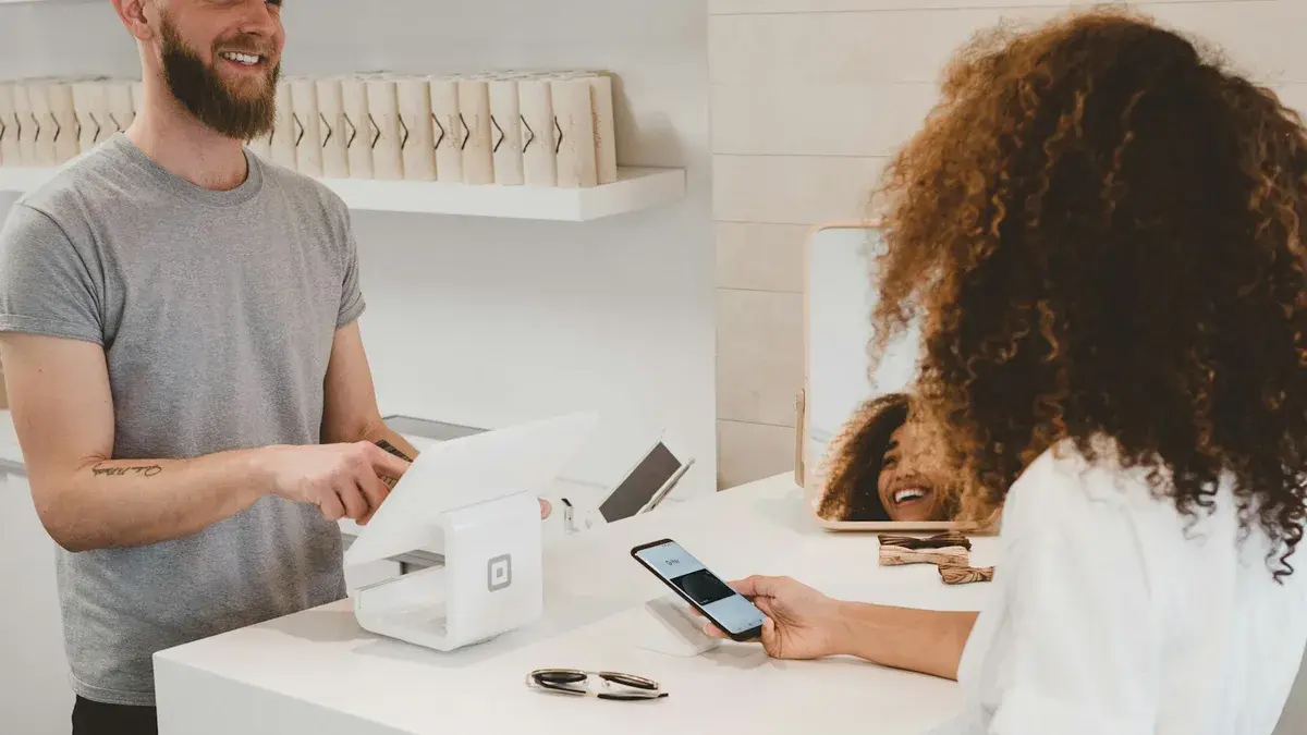 Happy customer paying at a bright modern shop counter after finding the business online