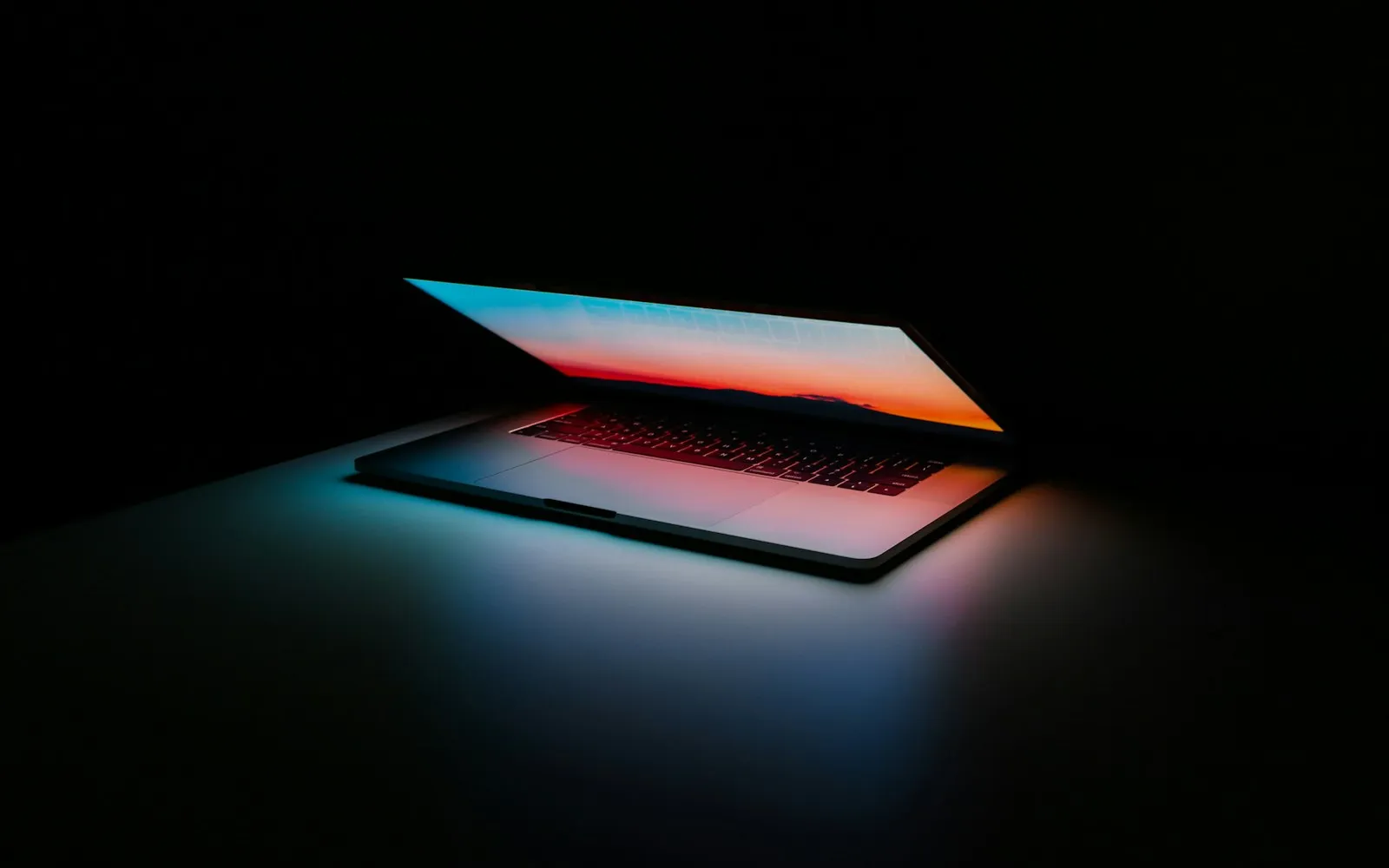 Developer workspace with a laptop glowing in a dark modern office